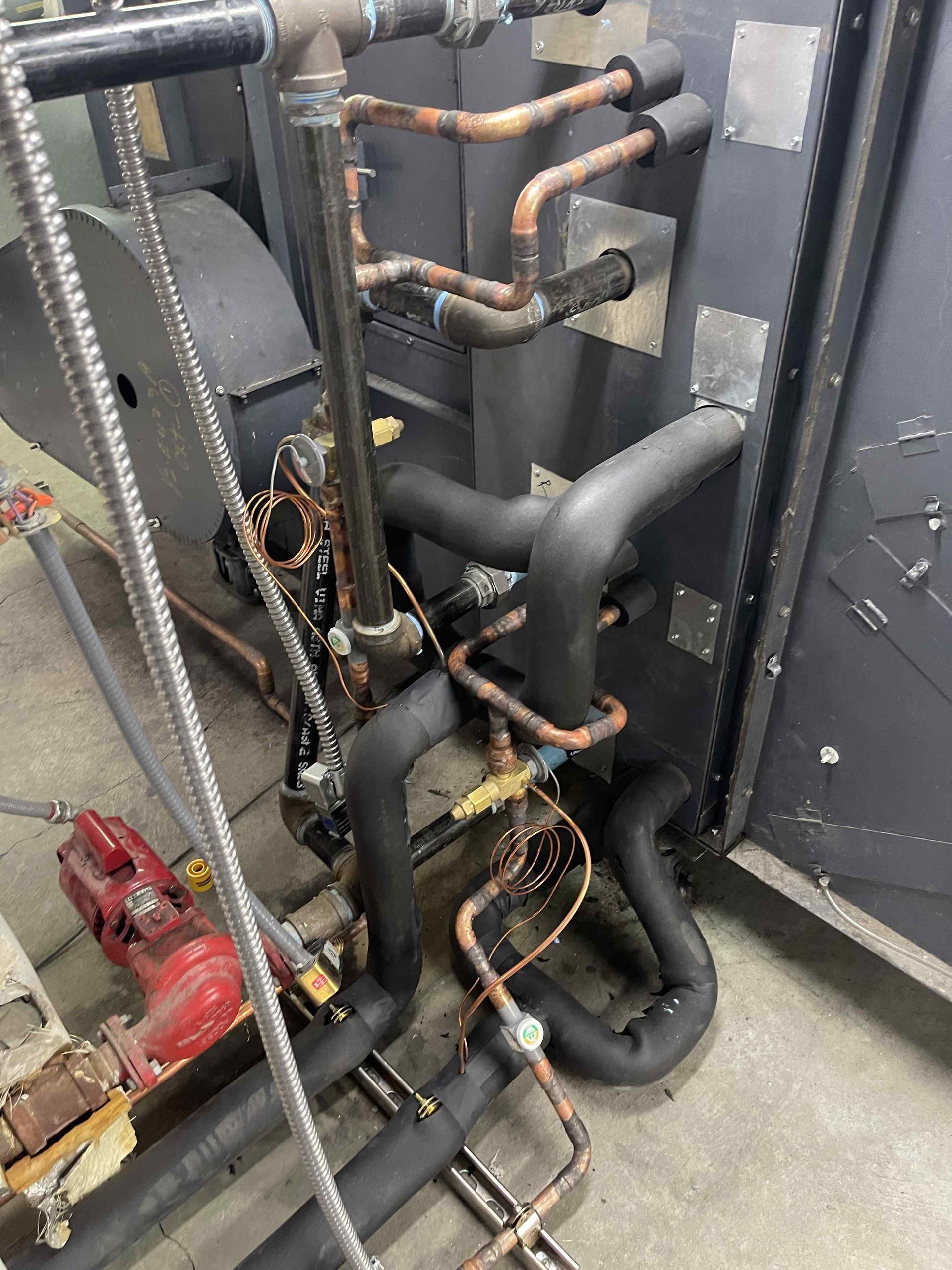 HVAC system with copper pipes, black insulation, and a red valve, set in a metallic enclosure.