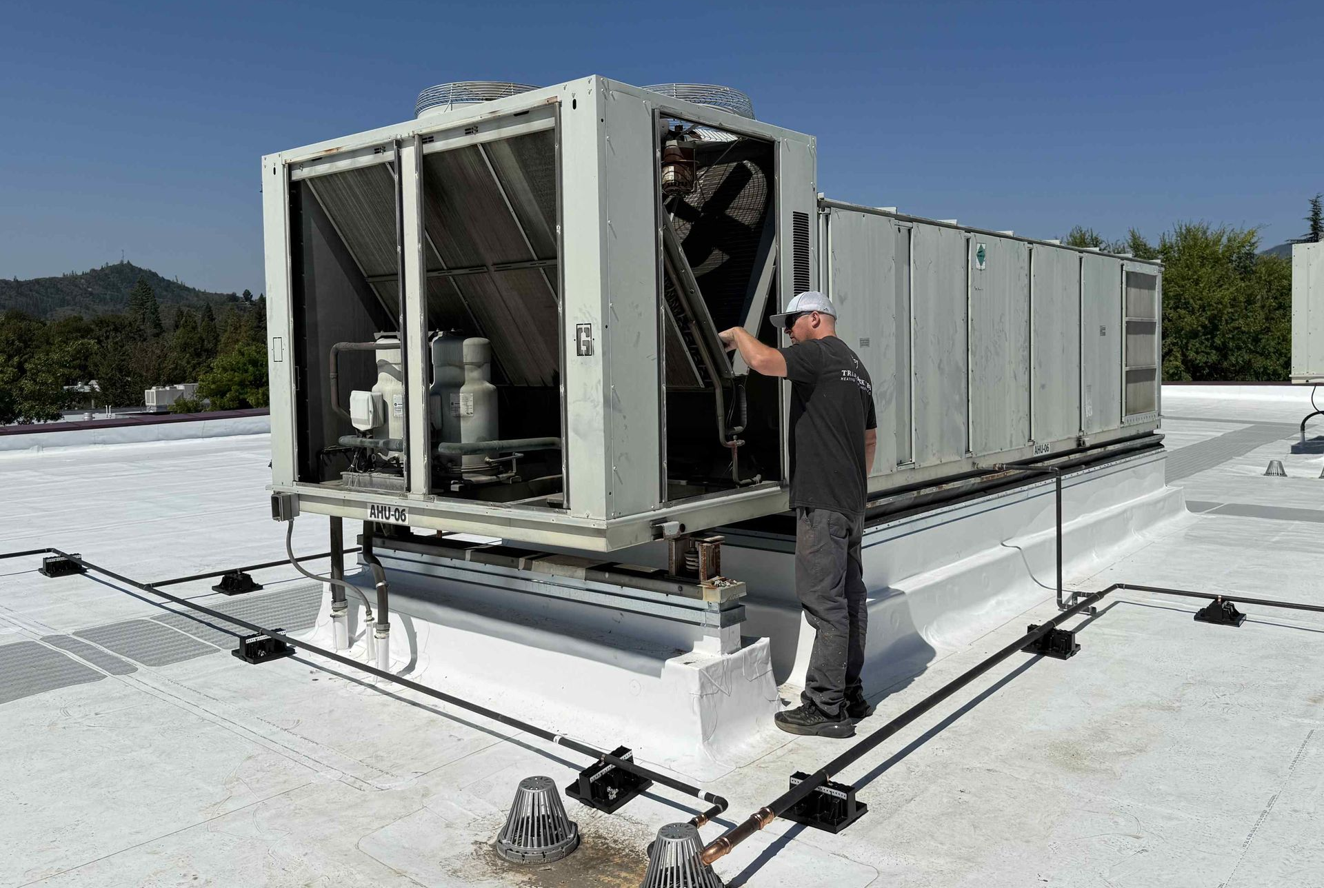 Man working on rooftop HVAC unit in Medford, Oregon.