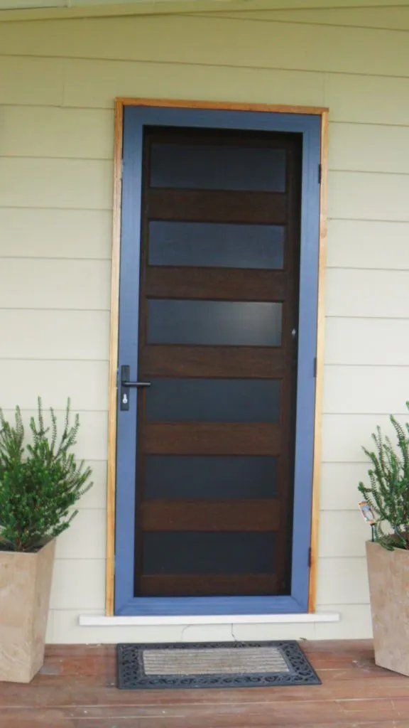 A Wooden Door with A Blue Frame Is Surrounded by Potted Plants — Manning Valley Patios in Cundletown, NSW