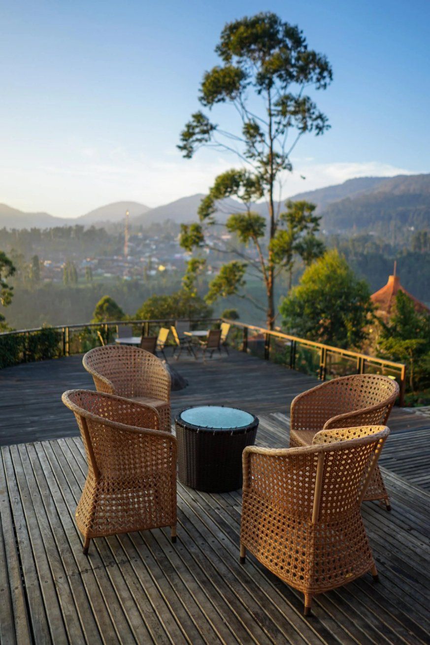 A Wooden Deck with Wicker Chairs and A Table with A View of The Mountains —Manning Valley Patios in Old Bar, NSW