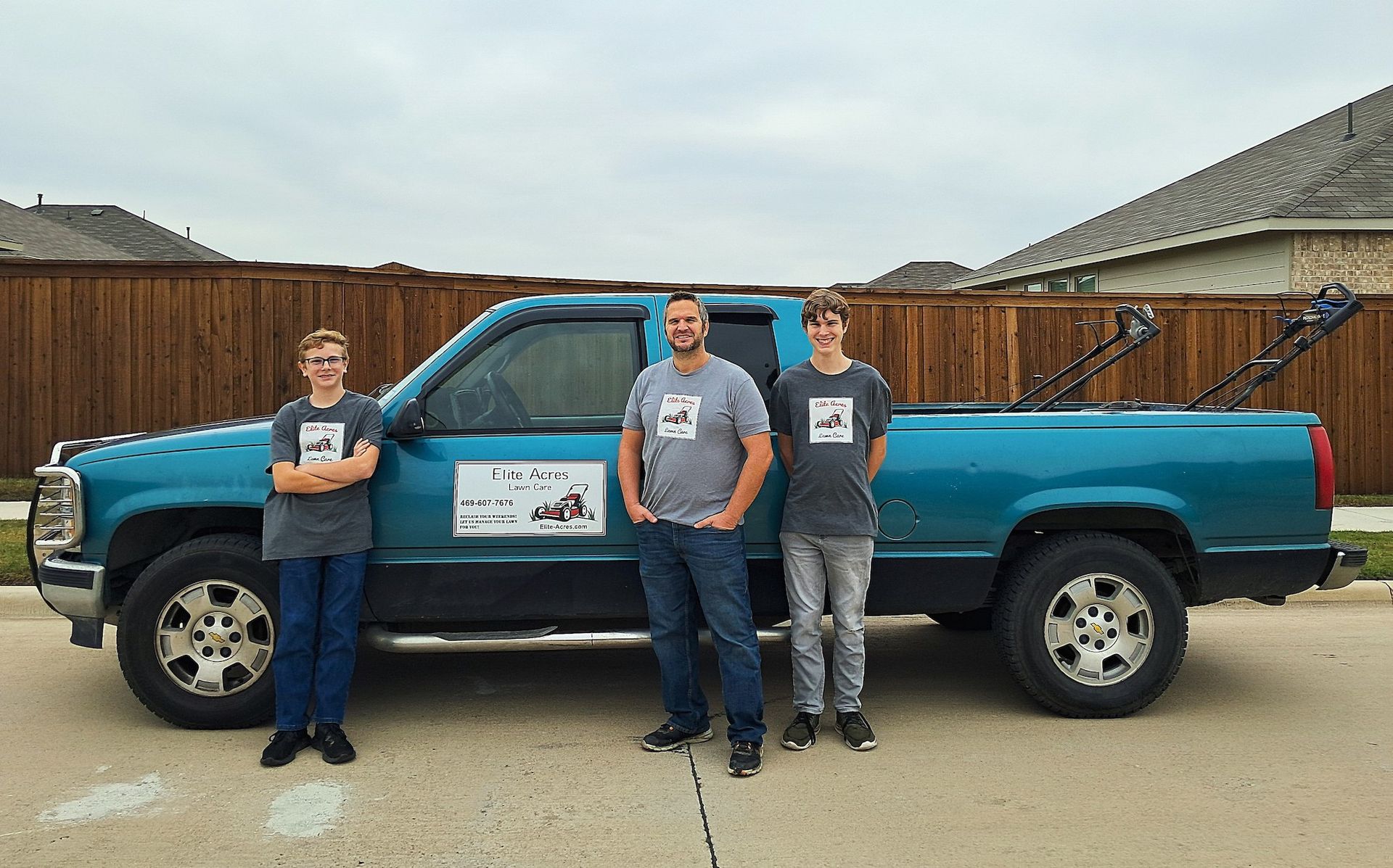 Three men are standing next to a blue truck.