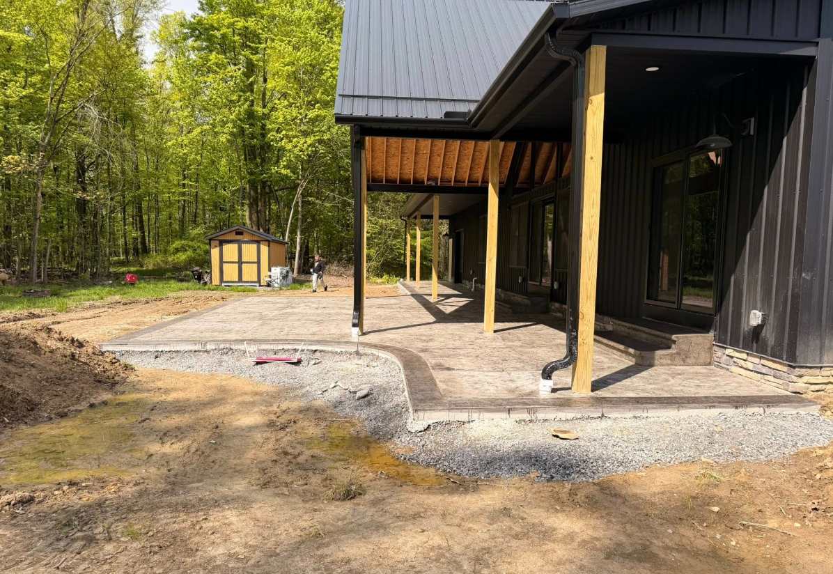 Modern house exterior with gravel patio, covered porch, and wooded yard