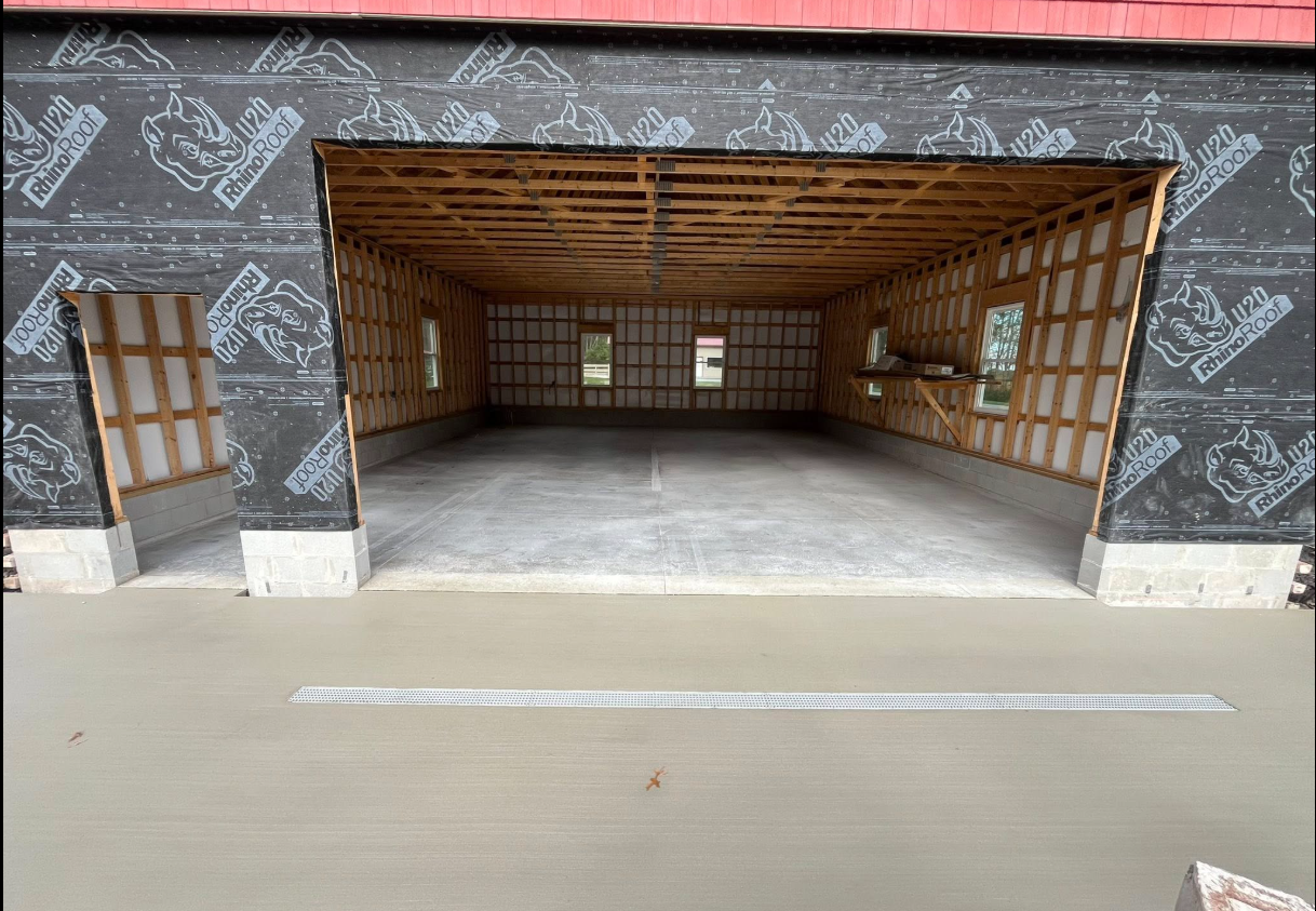 Empty unfinished room with exposed wood ceiling and dark patterned walls, viewed from the entrance