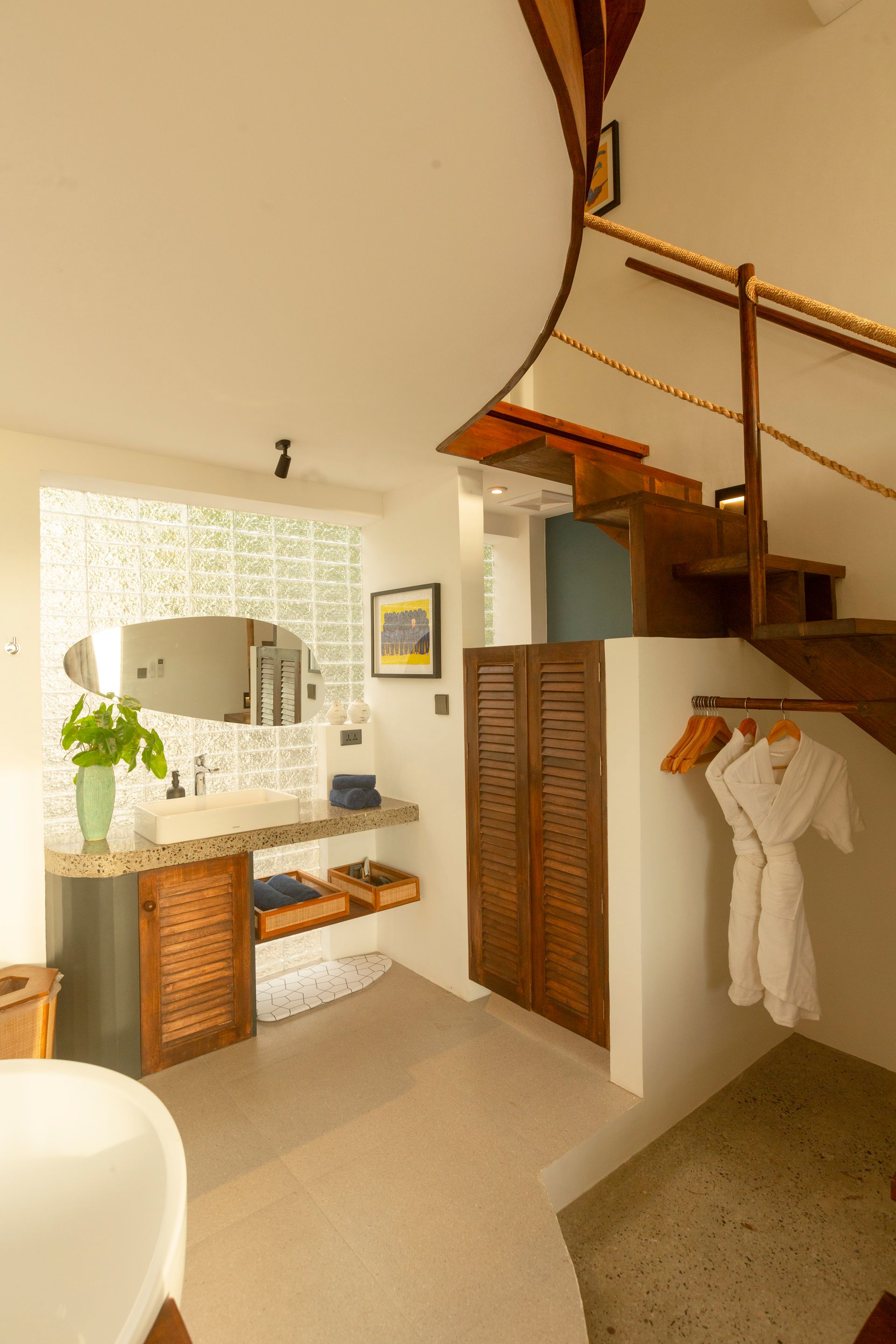 Bathroom with wooden spiral staircase and vanity area. Robe hanging on wall.