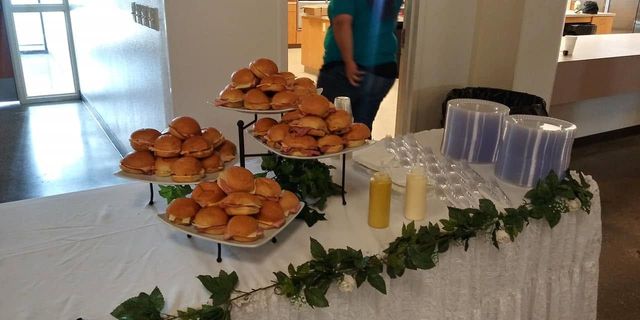 Muffin buffet on a table with greenery, napkins, cups, and yellow drinks in a bright room