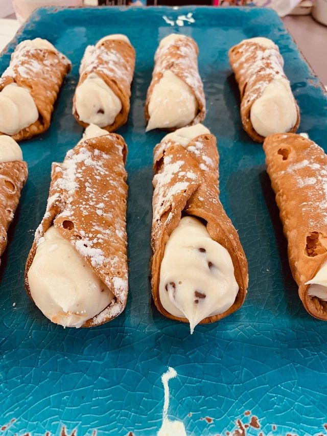 Tray of powdered pastry cones filled with cream on a blue surface