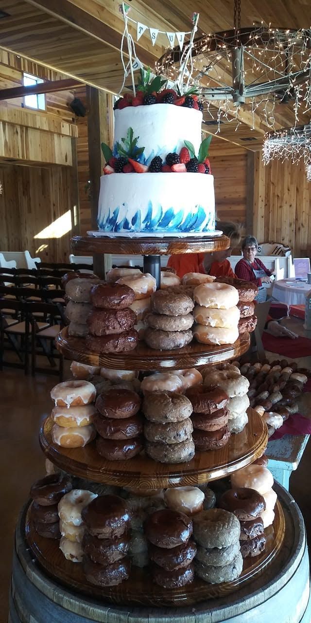 Tiered dessert display with white frosted cake and stacked pastries in a rustic banquet hall