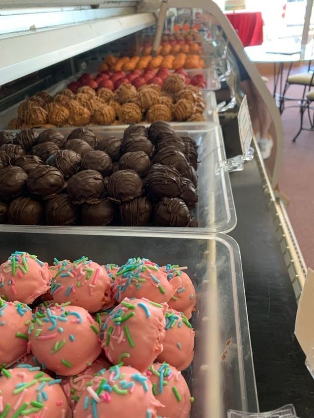 Trays of assorted decorated donuts in a bakery display case