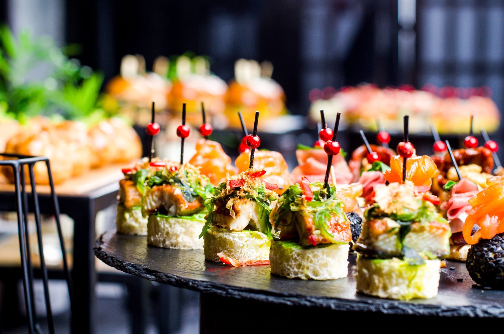 Elegant sushi appetizer tray with colorful garnishes and skewers at a catered event