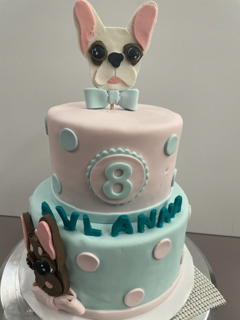 Pastel bunny-themed two-tier cake with polka dots, number 8 topper, and teal “YLANA” lettering
