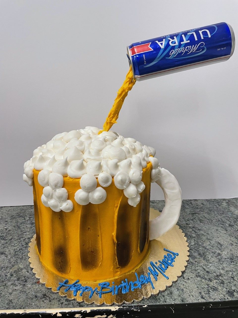 Beer mug made of candy, with a blue soda can pouring foam on a gray background