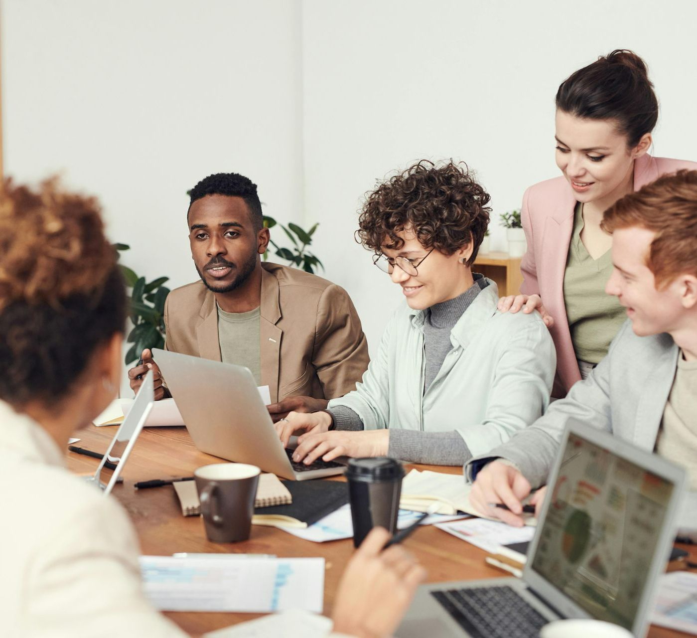 A group of people are sitting around a table with laptops.