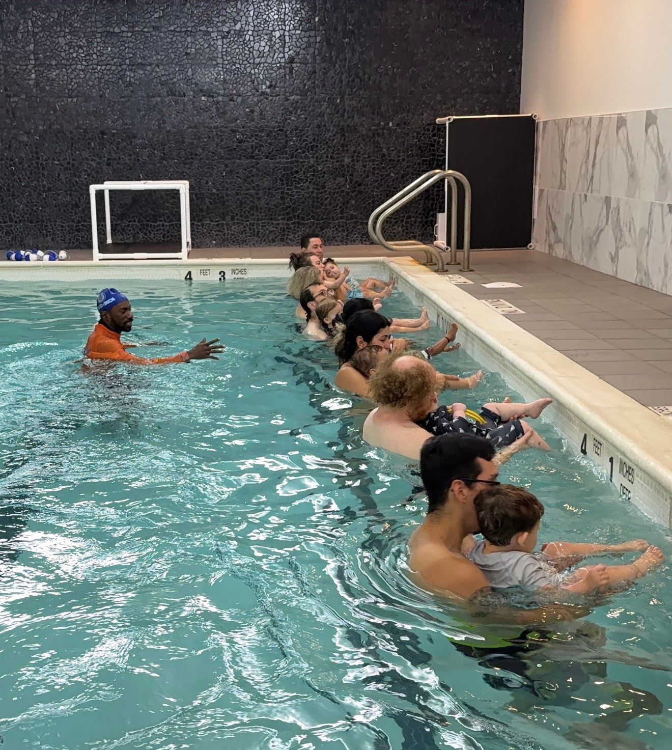 Group of swimmers and instructor smiling in a pool.
