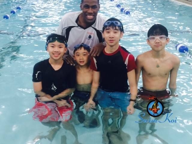 Group of swimmers and instructor smiling in a pool.