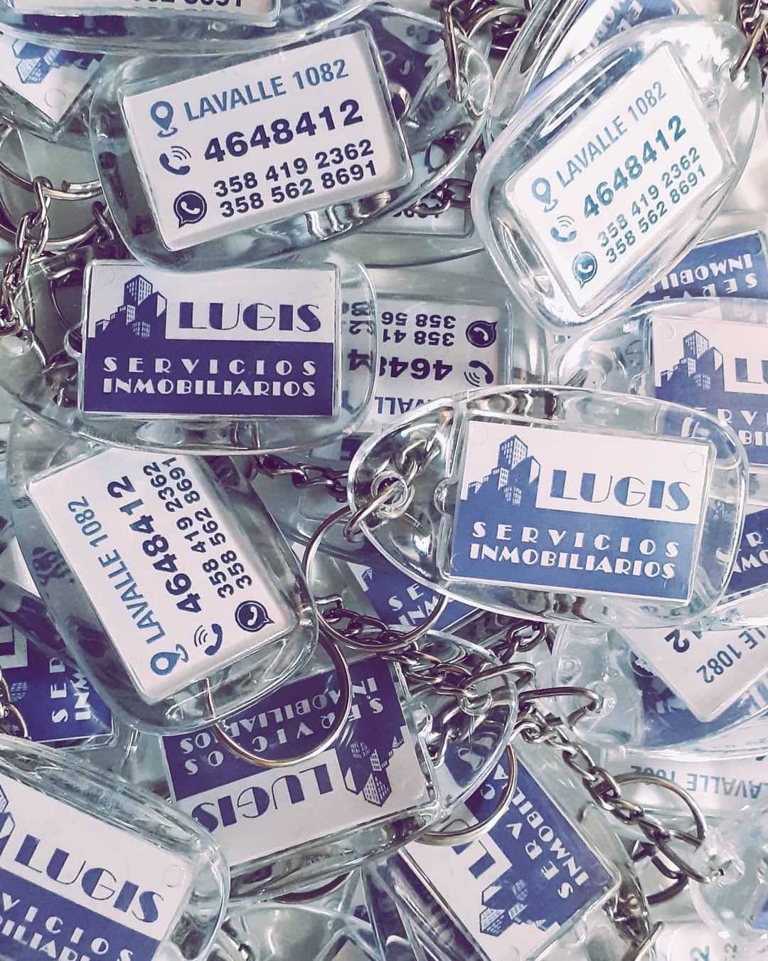 Montón de bolsos Lucs Selys blancos y azules con correas de cadena plateadas y etiquetas con texto en francés.