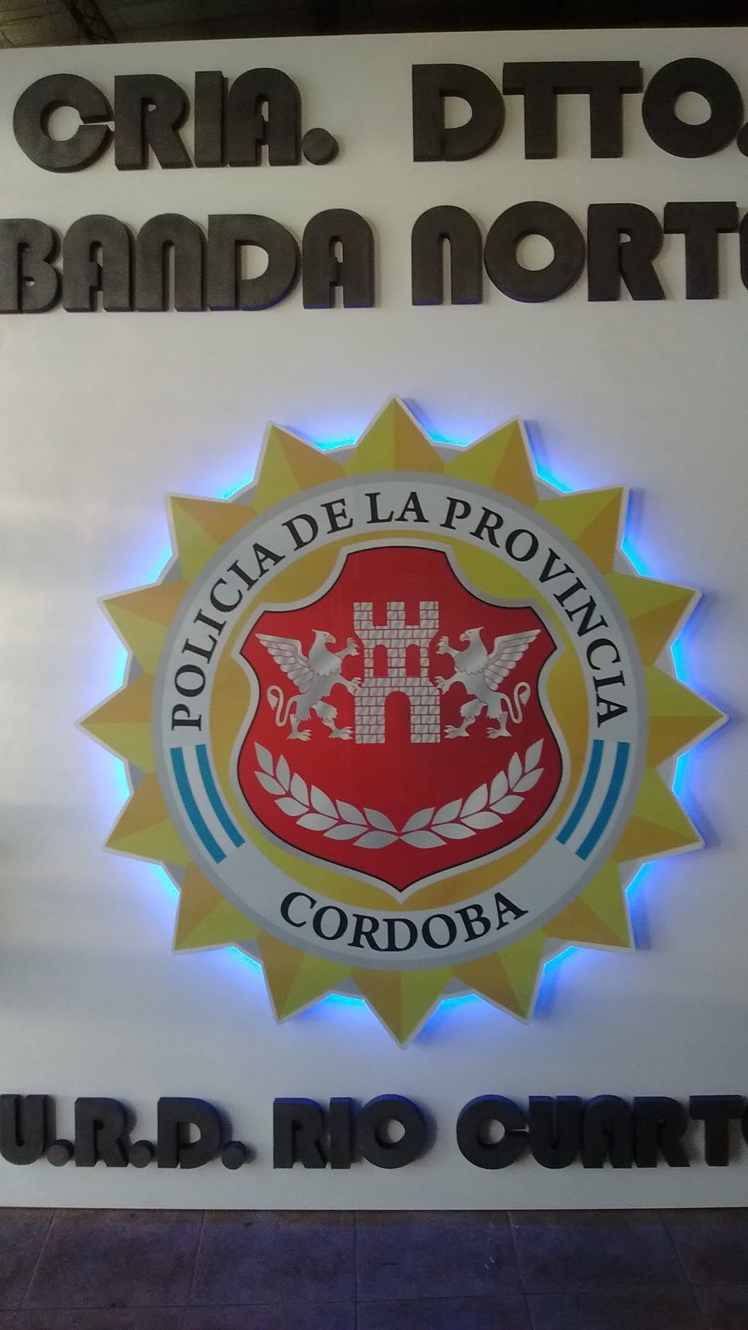 Insignia de la Policía de la Provincia de Córdoba sobre pared con texto negro alrededor