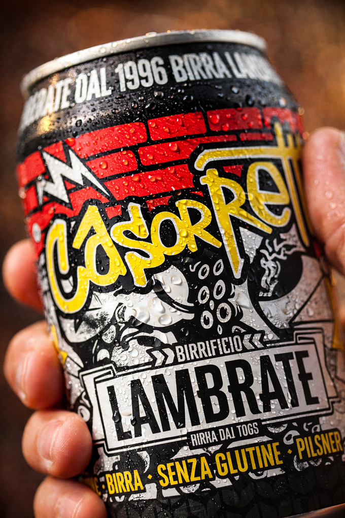 Hand holding a craft beer can with colorful graffiti-style label reading “Casper” and “Lambbrate.”