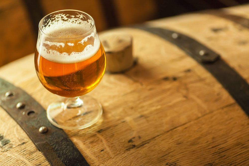 A glass of beer on a wooden barrel in warm light