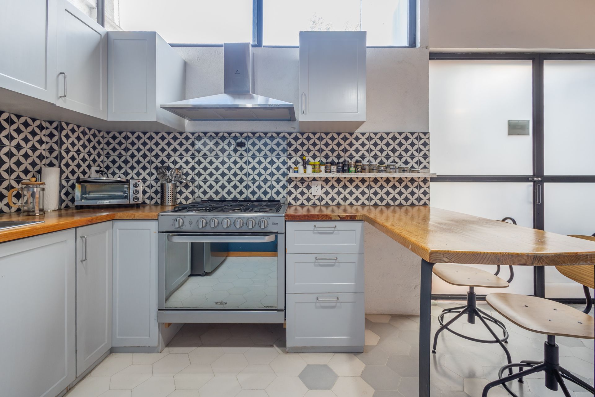 Una cocina con gabinetes blancos, una estufa, una mesa y sillas.