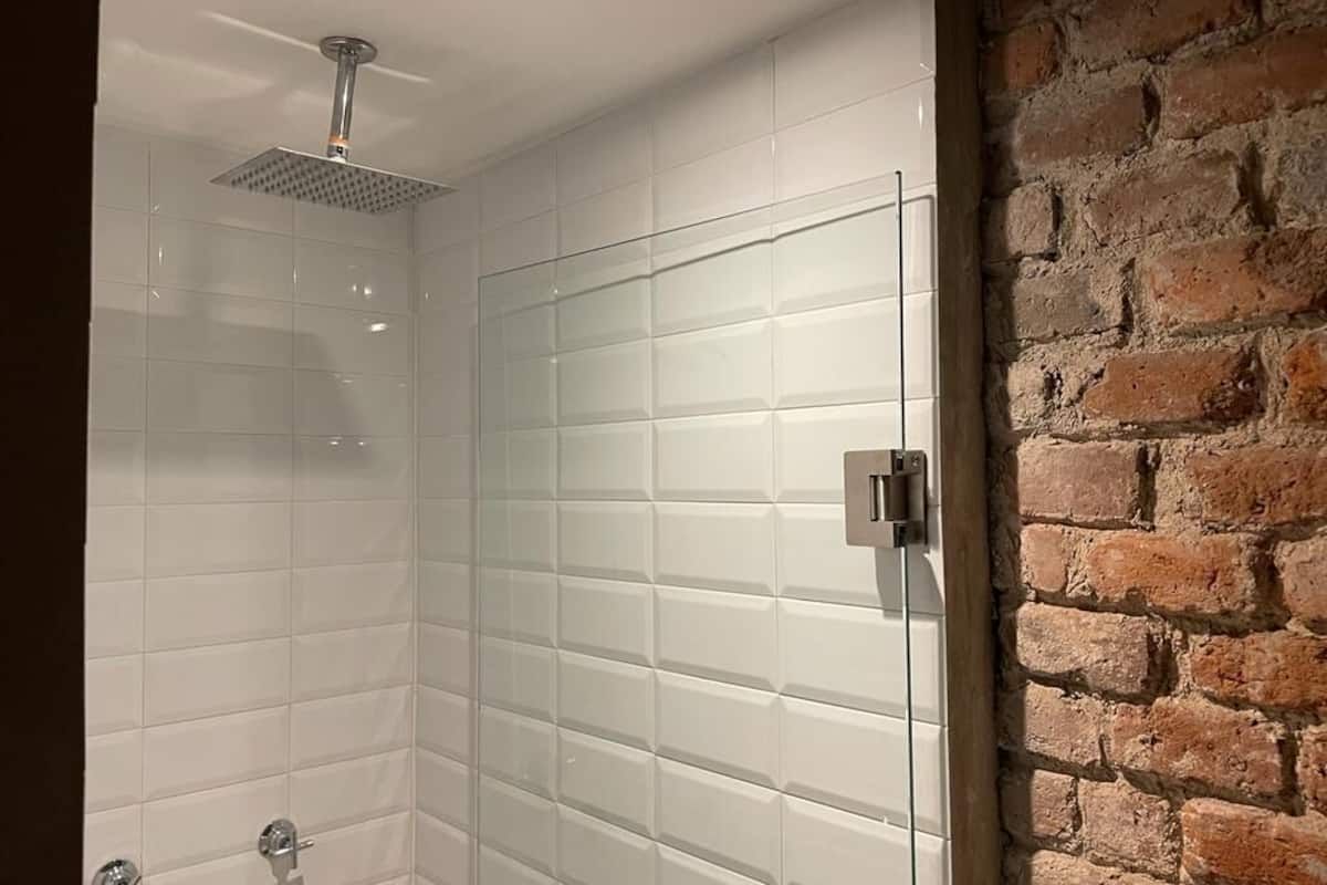 Un baño con ducha y una pared de ladrillo.