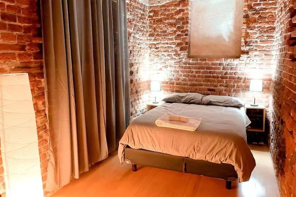 Un dormitorio con una cama y una pared de ladrillos.