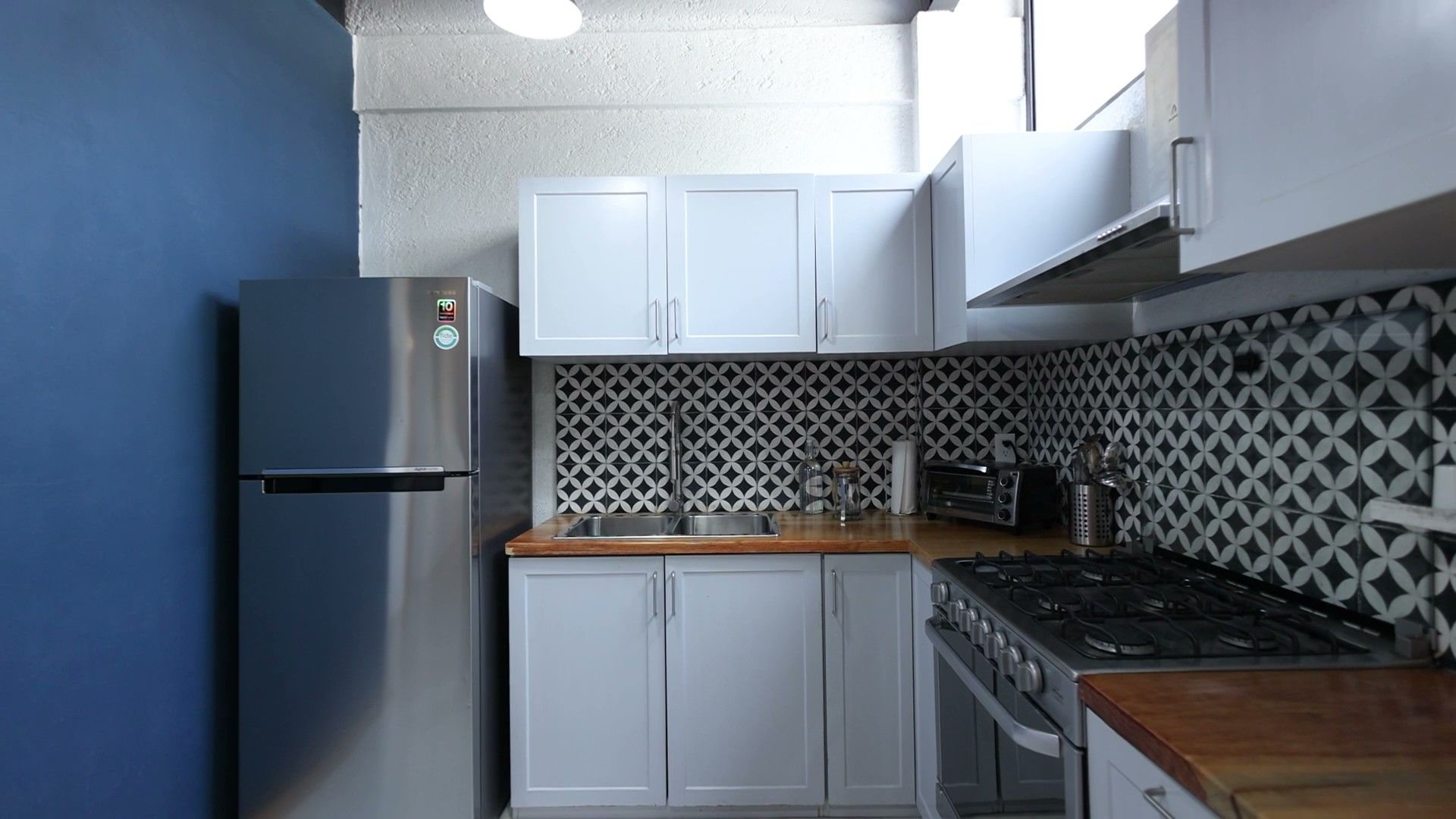 Una cocina con gabinetes blancos, un refrigerador de acero inoxidable, una estufa y un fregadero.