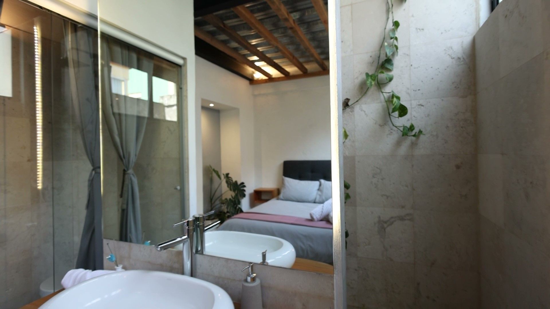 Un baño con un lavabo y una cama al fondo.