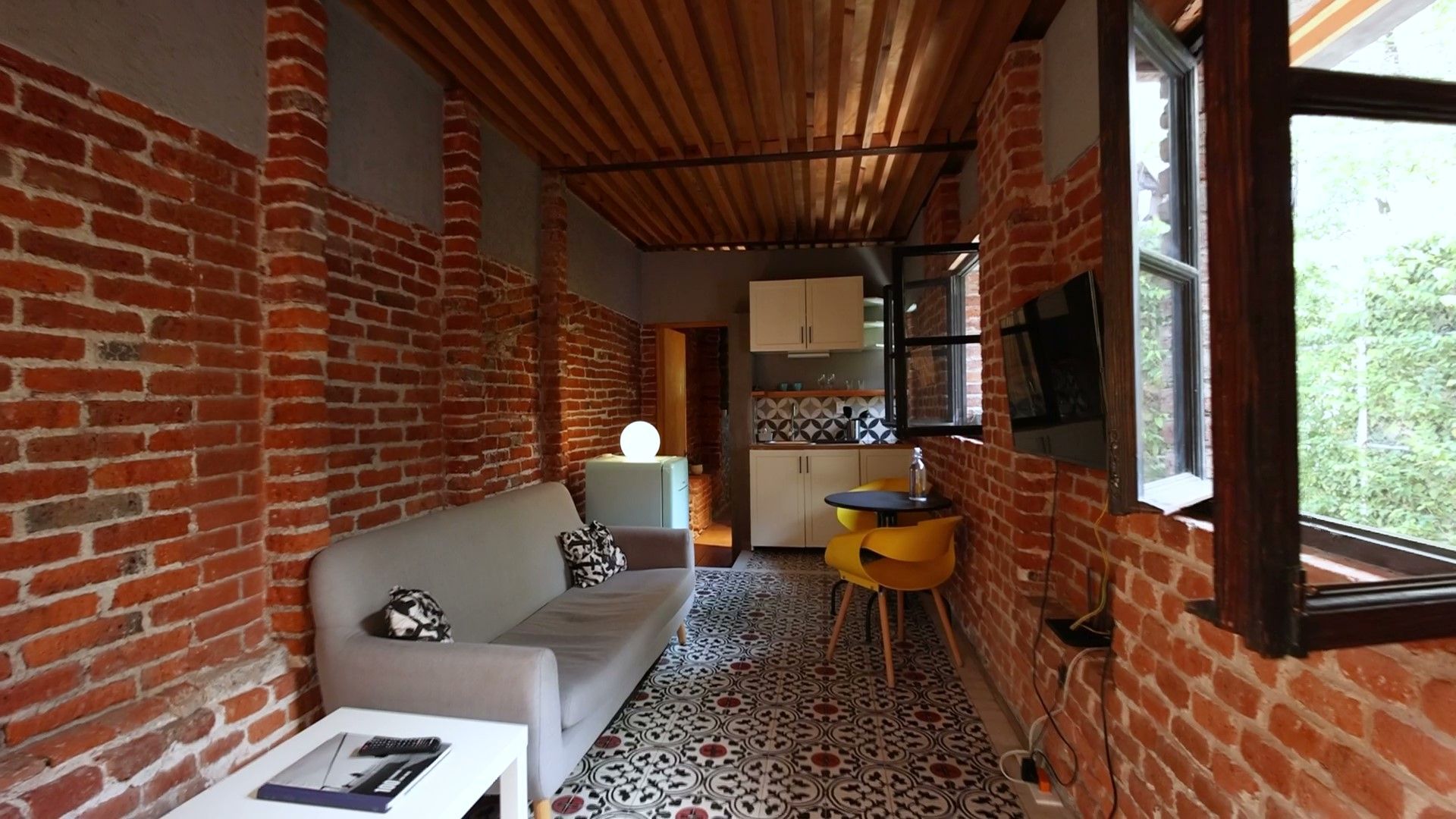 Una sala de estar con un sofá, una mesa, sillas y una ventana.