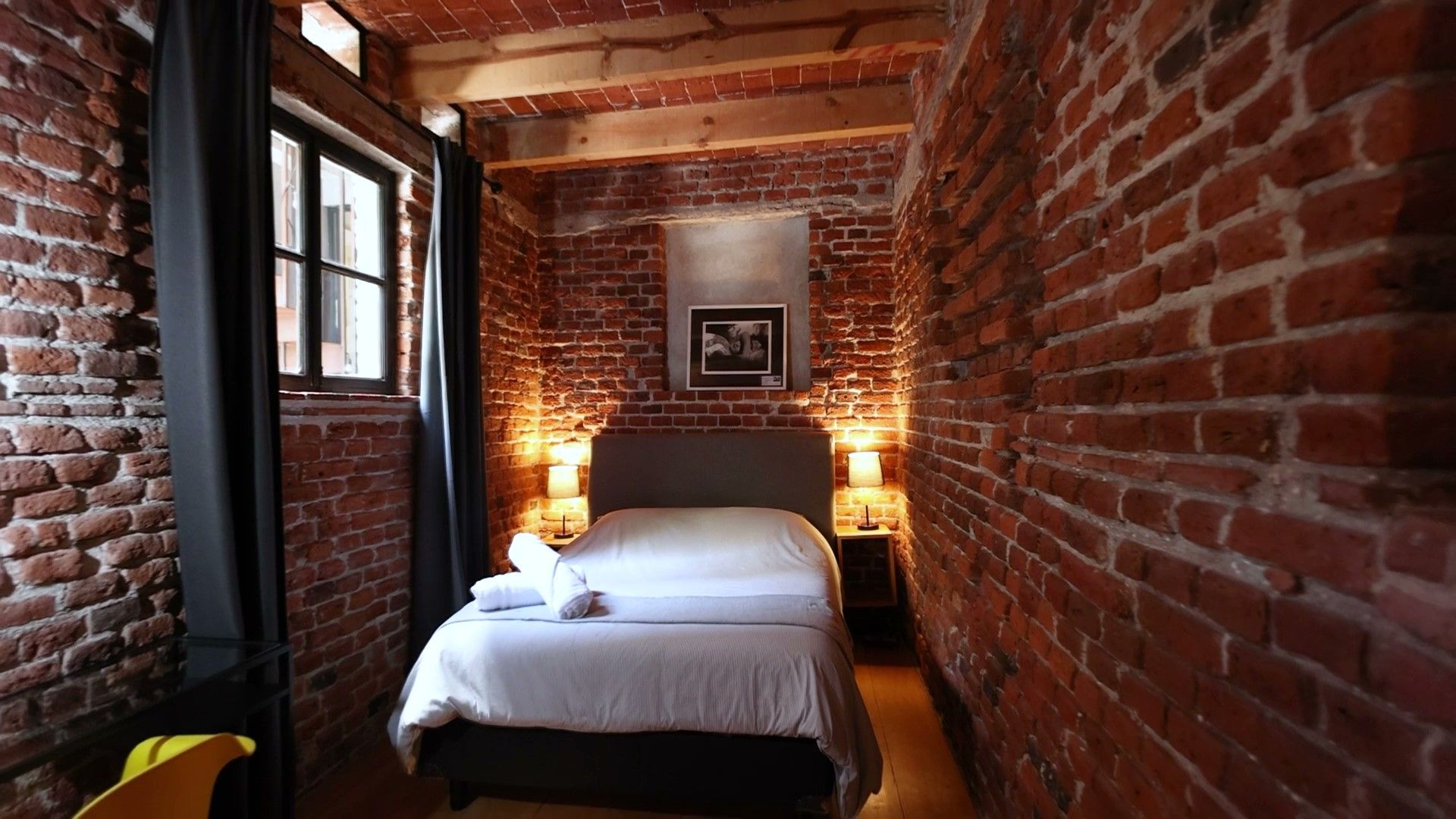 Un dormitorio con una cama y una pared de ladrillos.