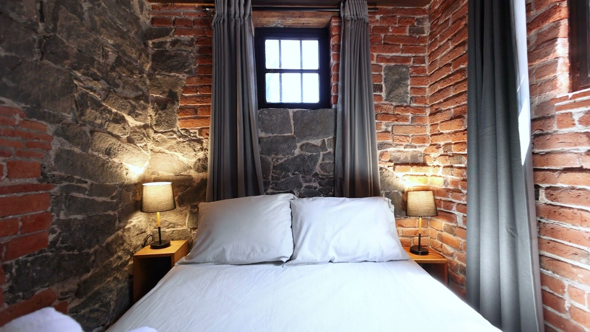 Un dormitorio con una cama y una pared de ladrillos.