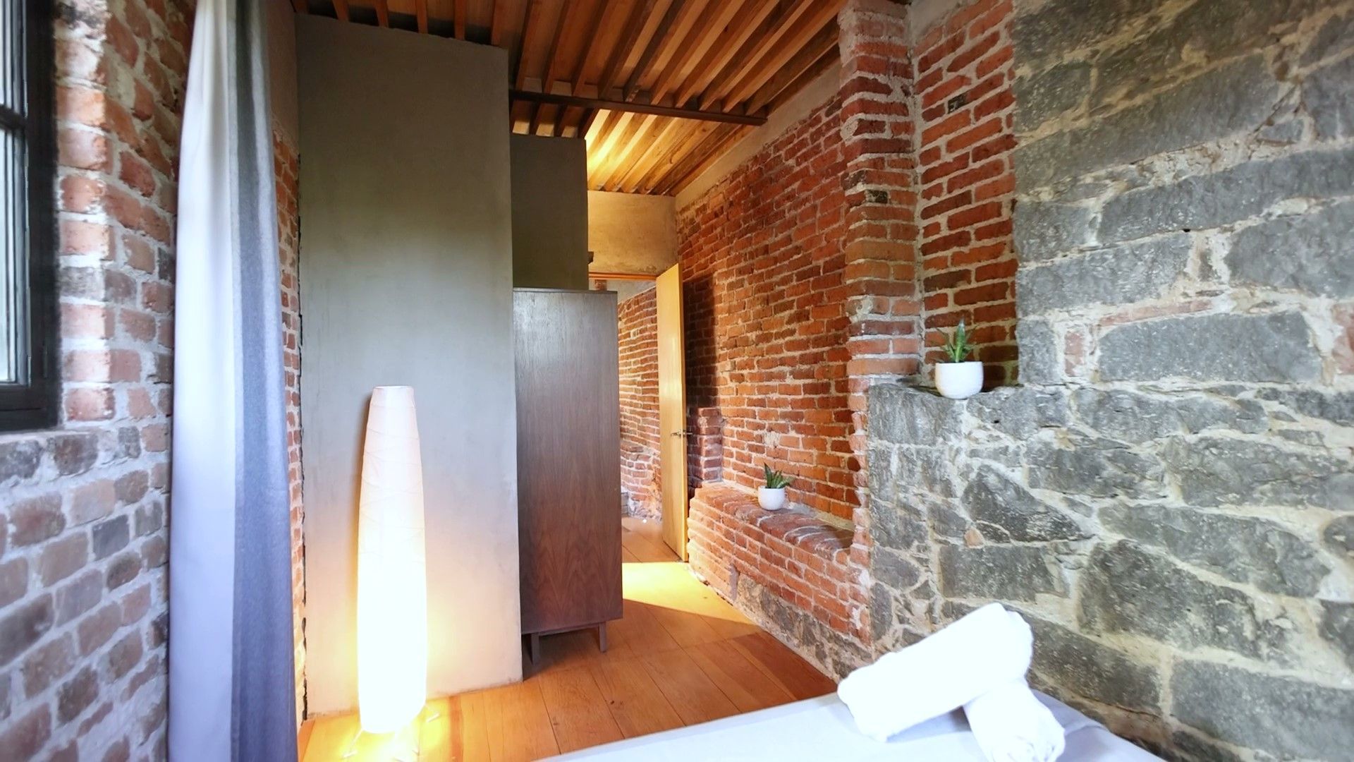 Un dormitorio con una pared de ladrillos y una cama con toallas encima.