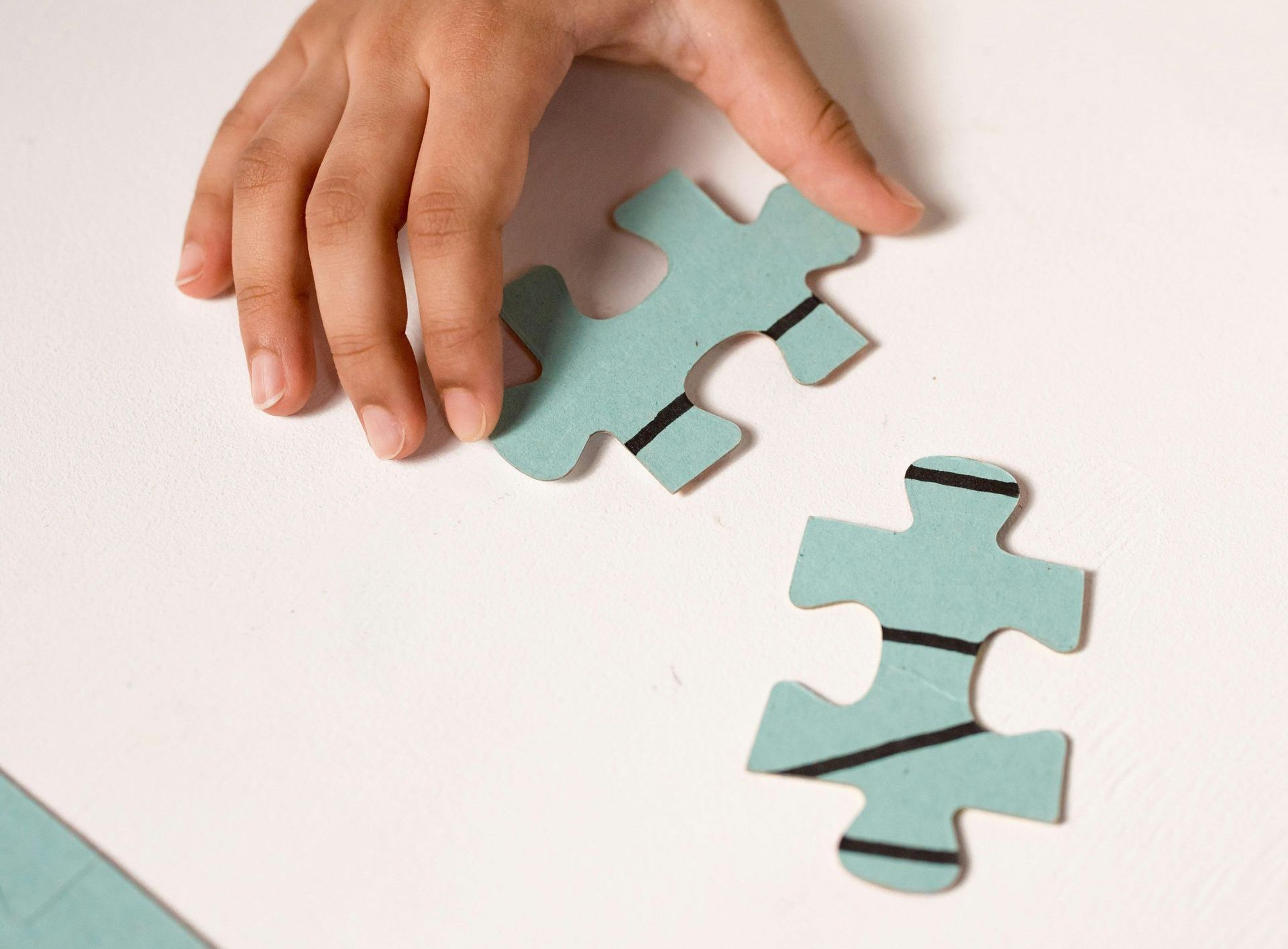 A hand fitting 2 puzzle pieces together - Save on Land Tax by Consolidating Property Titles with Farren Land Surveys