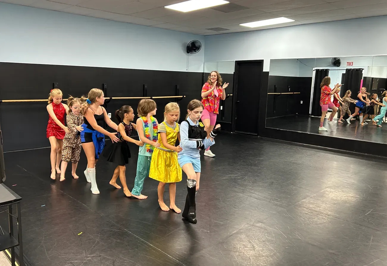 Children practicing dance routines in a studio with mirrors and black walls