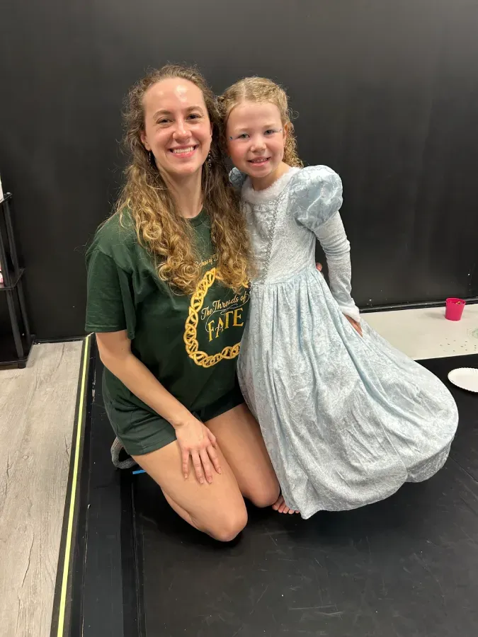 Ms. Sidney taking a knee and smiling with one of her dance campers