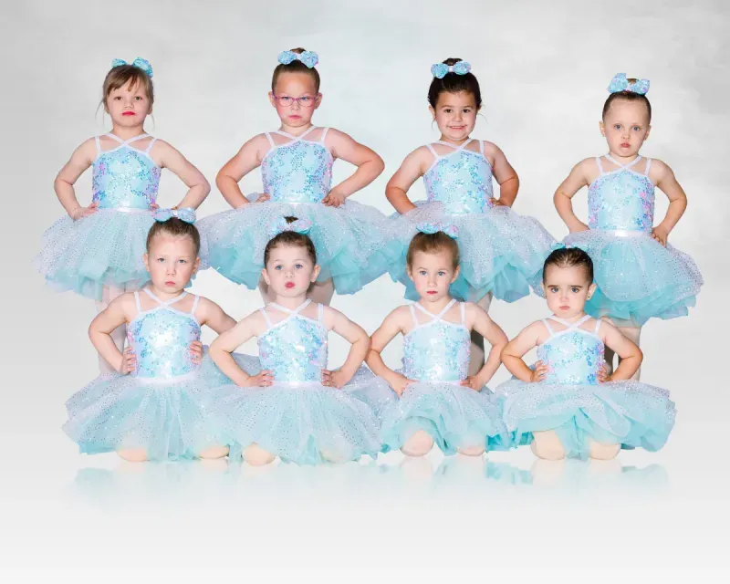 Eight children in blue ballet tutus posing in two rows against a white background.