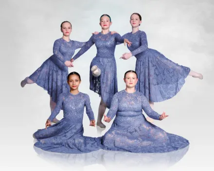 Five dancers in matching blue dresses pose against a white background.