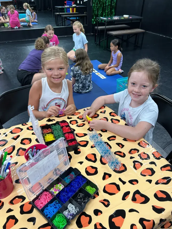 Children doing a colorful bead activity at a table in a dance studio