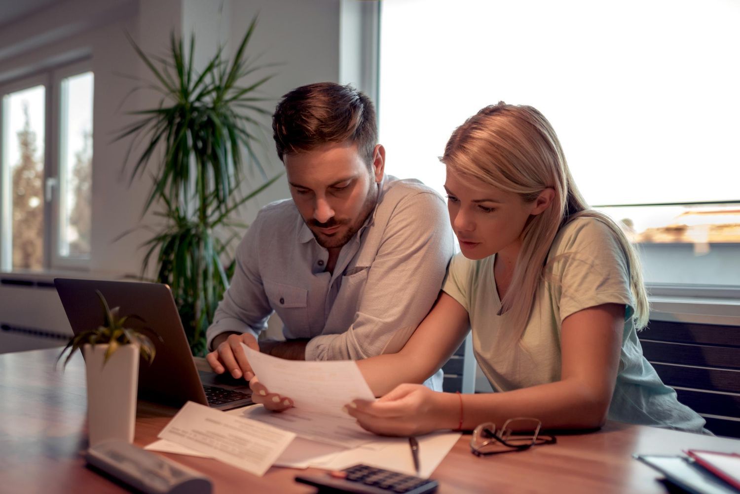 Two coworkers reviewing documents at a desk in a bright office