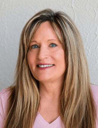 Smiling woman with long blonde hair in a pink top against a light textured background