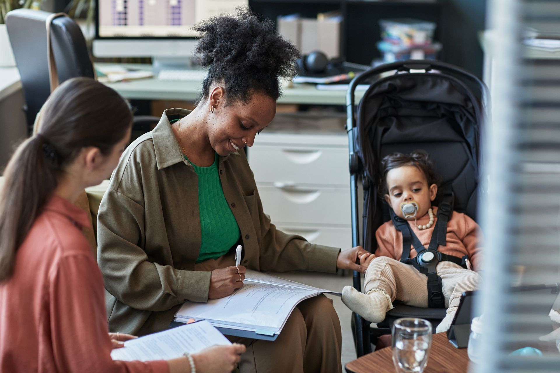 Counselor taking notes while meeting with a parent and child in an office room