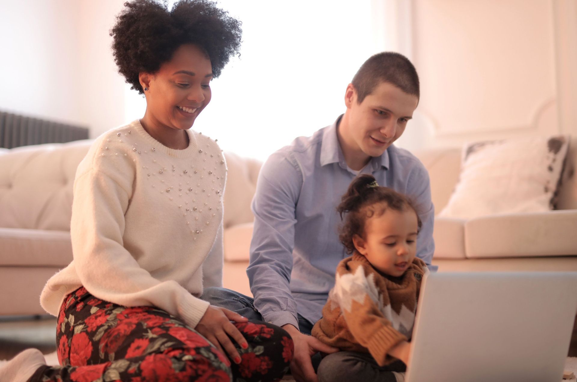 Three people seated around a coffee table reviewing papers and a tablet in a living room