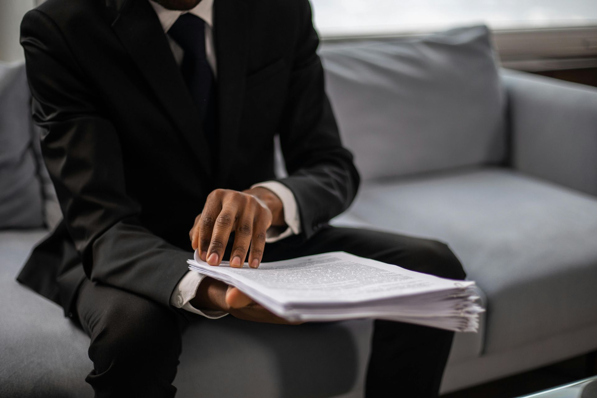 Businessperson in a black suit reviewing papers on a couch