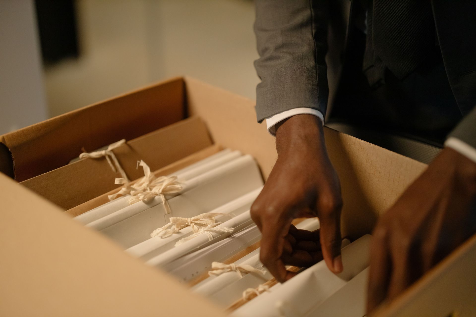 Hands packing white items into a cardboard box with packing material