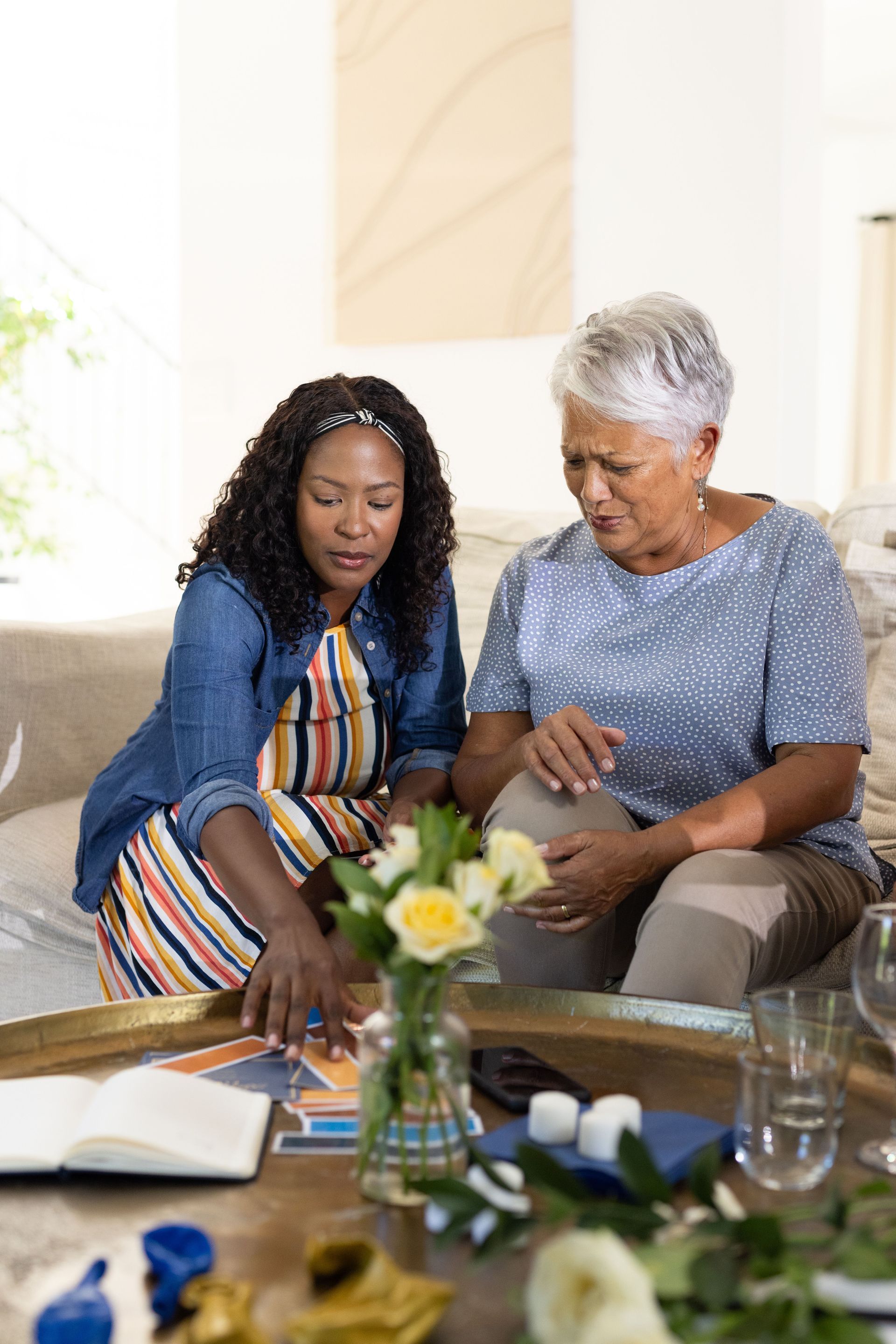 Two people reviewing papers on a couch beside a coffee table with flowers and books