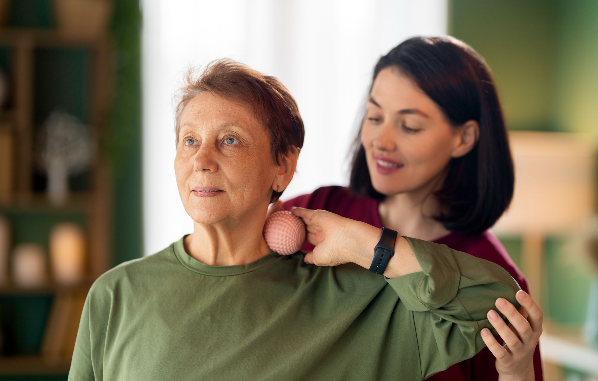 Woman giving another woman a shoulder massage in a warmly lit room
