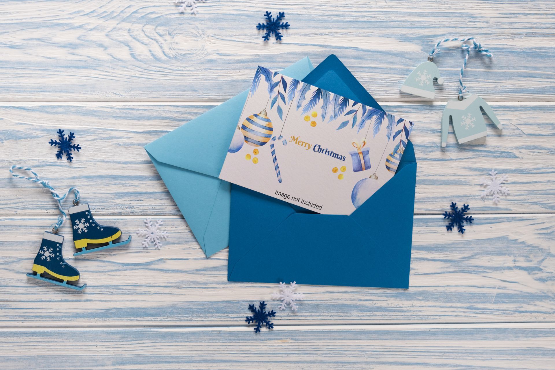 Blue envelope with a greeting card, decorated with snowflakes and winter-themed ornaments on a wooden surface.
