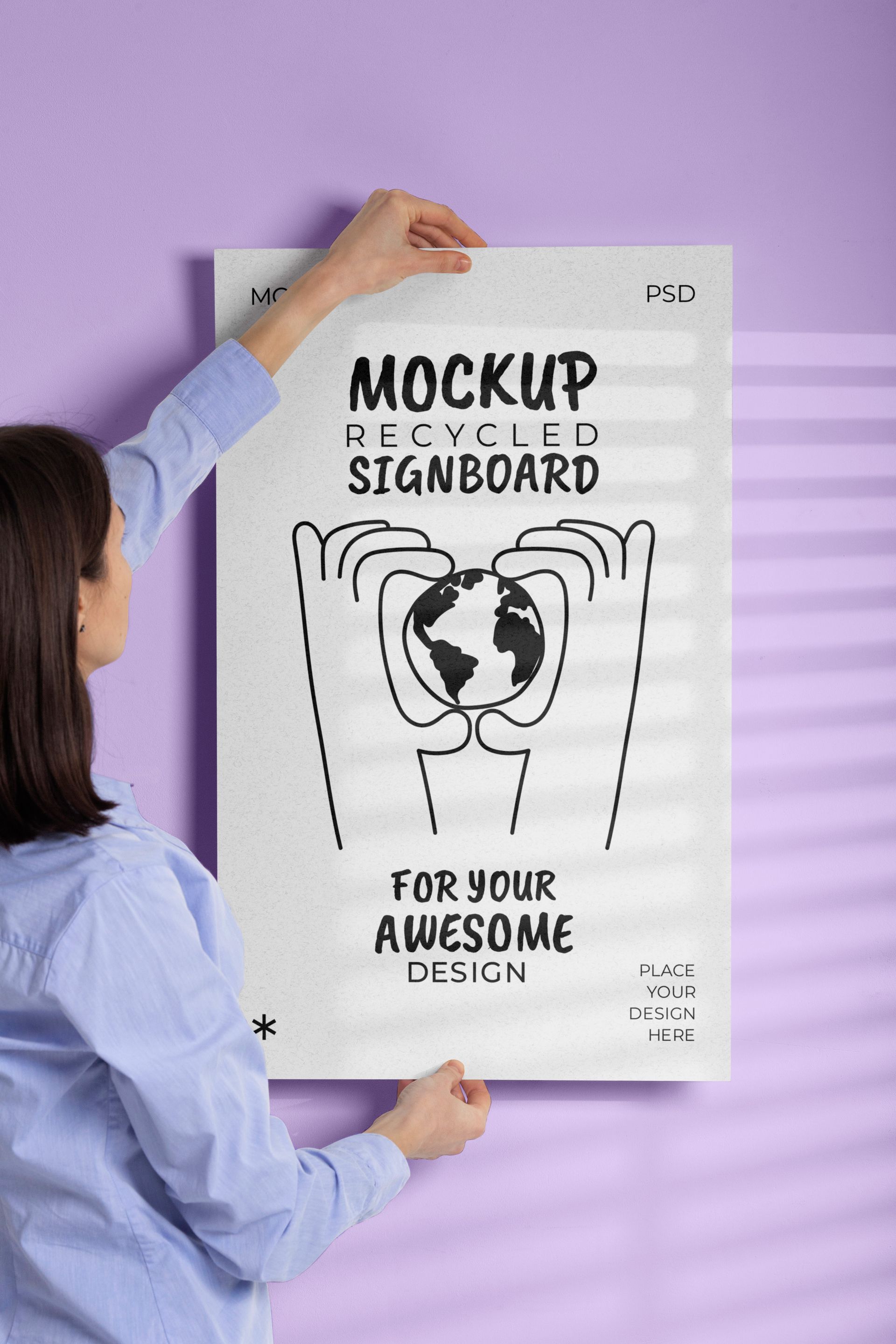 Woman hanging a poster with earth illustration on a purple wall.
