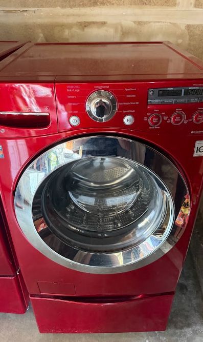 Red front-loading washing machine with a round glass door and control panel