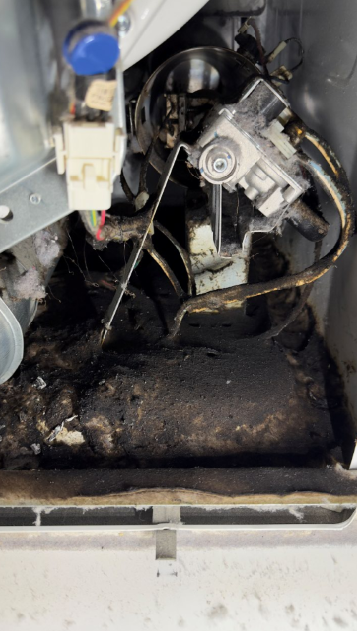 Greasy mechanical compartment with hoses, wiring, and metal parts inside an appliance or machine