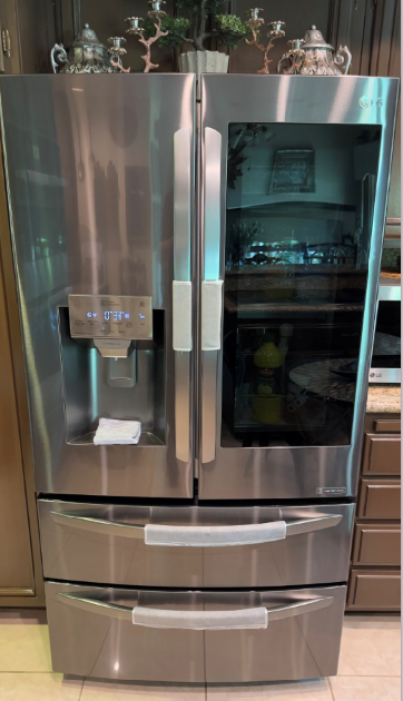 Stainless steel French door refrigerator with water and ice dispenser in a kitchen.